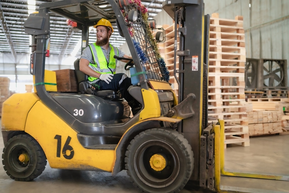 Warehouse,worker,wears,safety,helmet,driving,forklift,truck,in,pallet