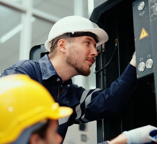 Two,caucasian,production,engineers,in,safety,wear,are,assisting,in