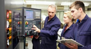 Engineer Teaching Apprentices To Use Computerized Lathe